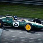 A green vintage Formula 1 car with number 25 speeds around a racetrack, showcasing classic racing heritage.