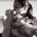 A woman gently kisses her cat, capturing a tender moment in black and white.