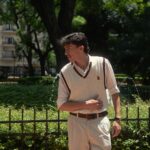 Portrait of a stylish young man standing confidently in a sunny Buenos Aires park.