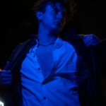 A dramatic urban portrait of a man under blue lighting, showcasing modern fashion and style.